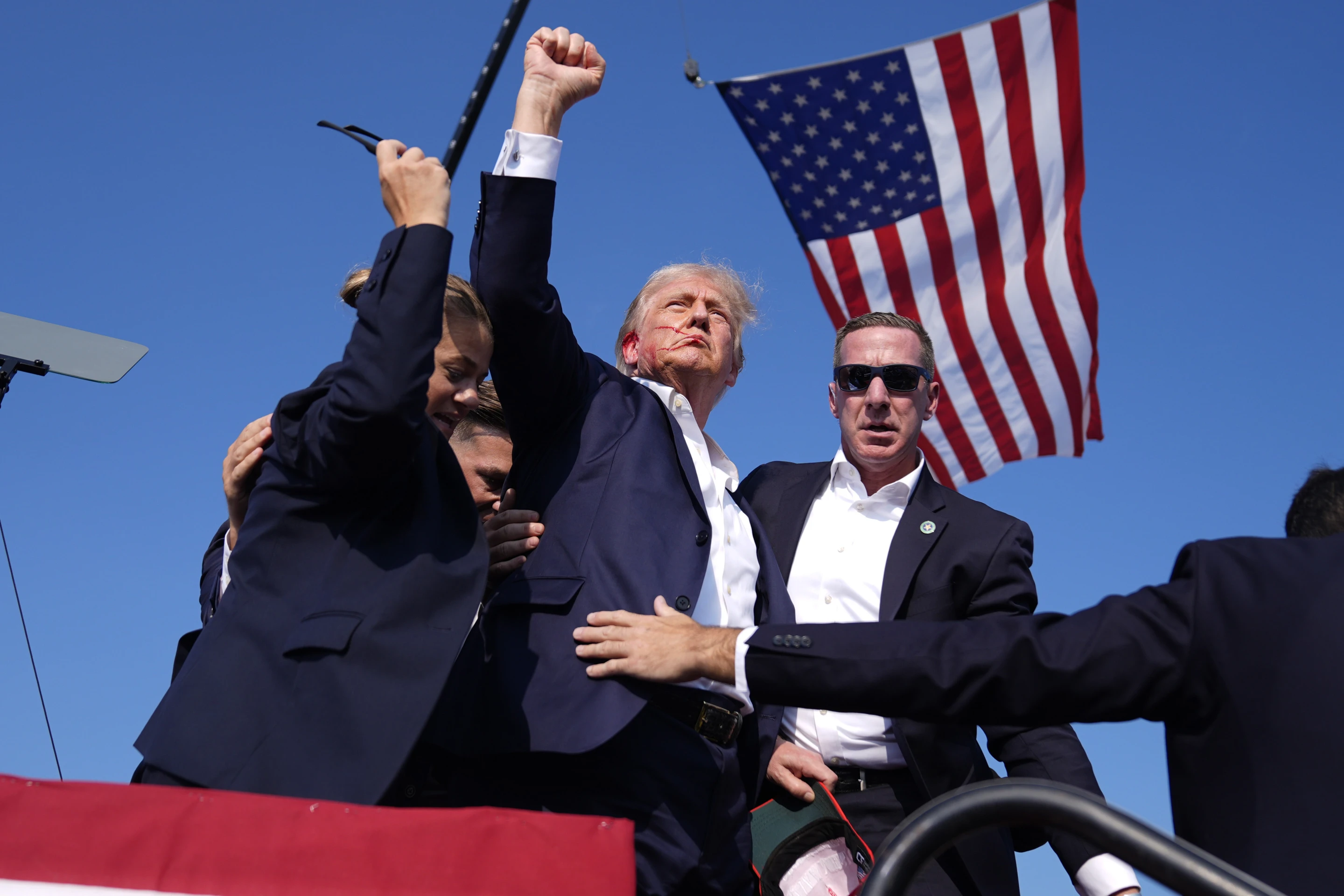 Photo shows Trump raising a fist into the air, with an angry look of strength and defiance. You can see by his lips he is saying the word 'Fight'