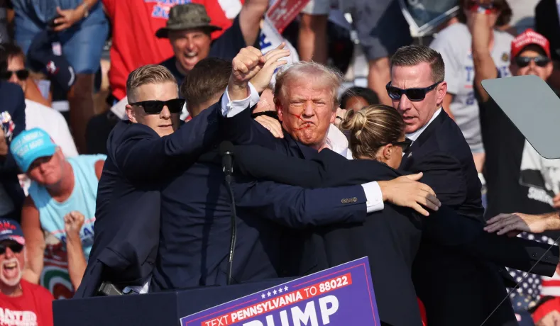 Photo shows Trump with his fist in the air and the American flag in the background.