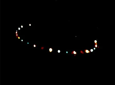 Dark photograph showing lights in the sky in a half circle formation.